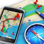 Mobile GPS navigation, travel and tourism concept: modern black glossy touchscreen smartphone with GPS navigation application, magnetic compass, pen and group of pushpins on city map isolated on white background